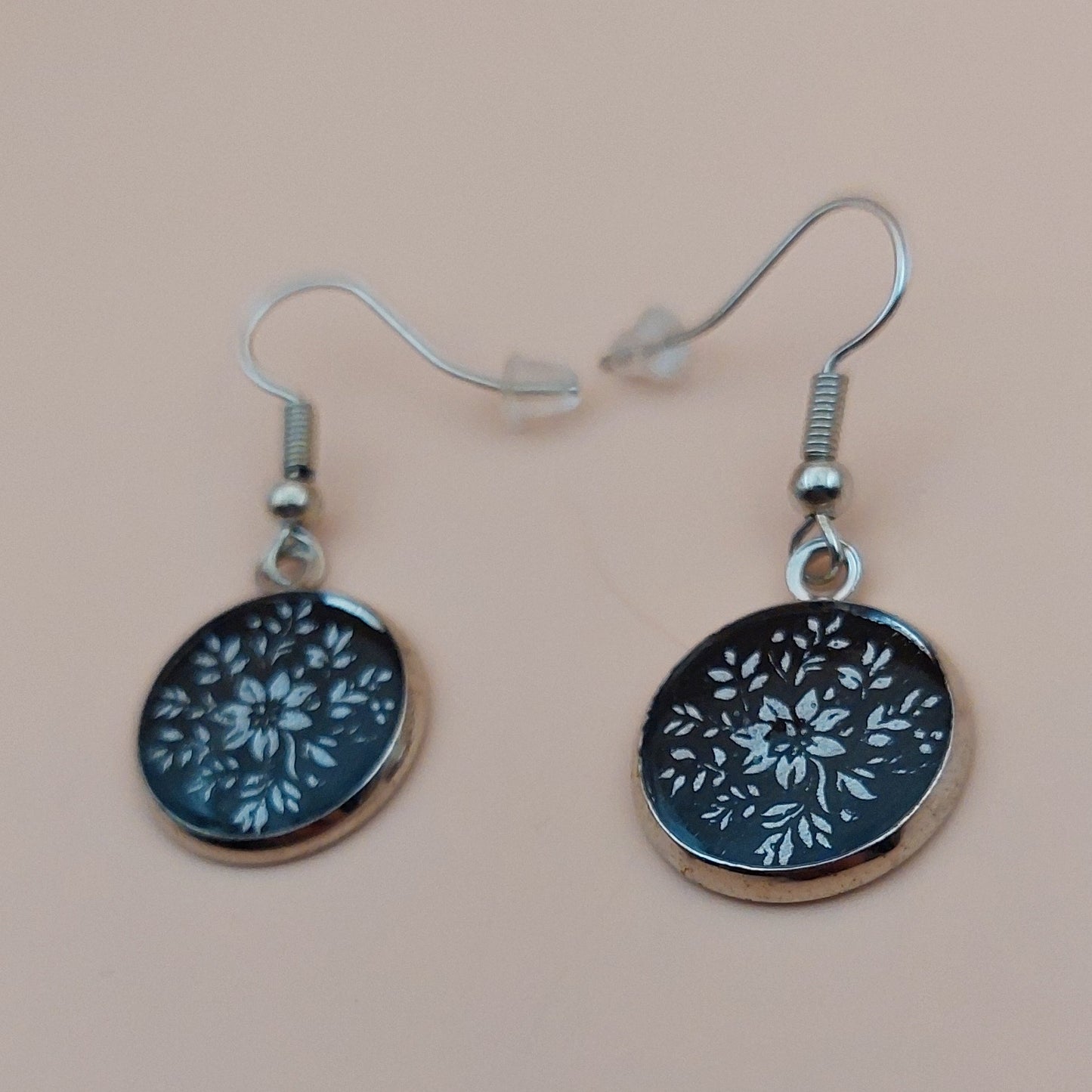 Two round keychains with floral patterns on a beige background