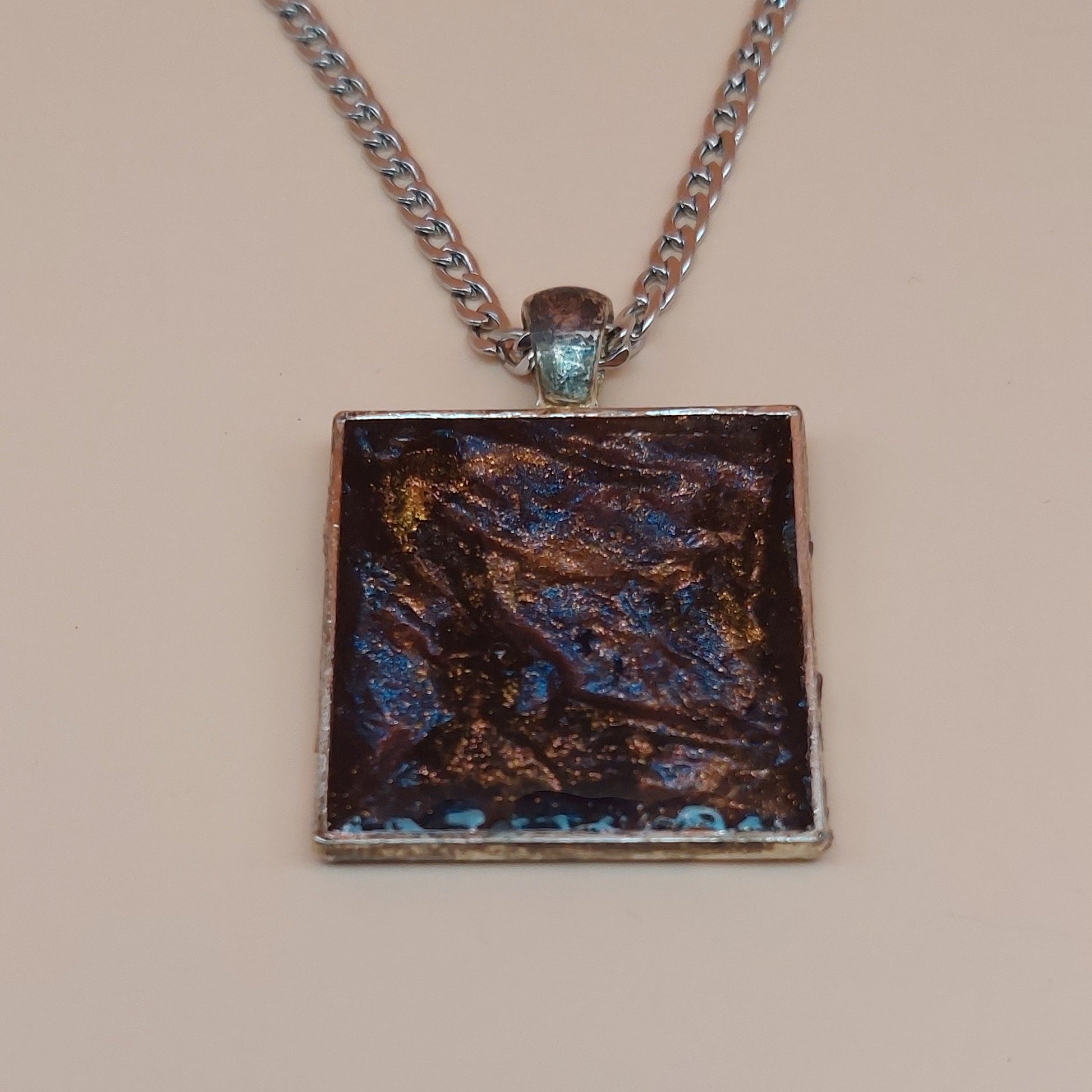Necklace with a square pendant featuring a textured design on a beige background