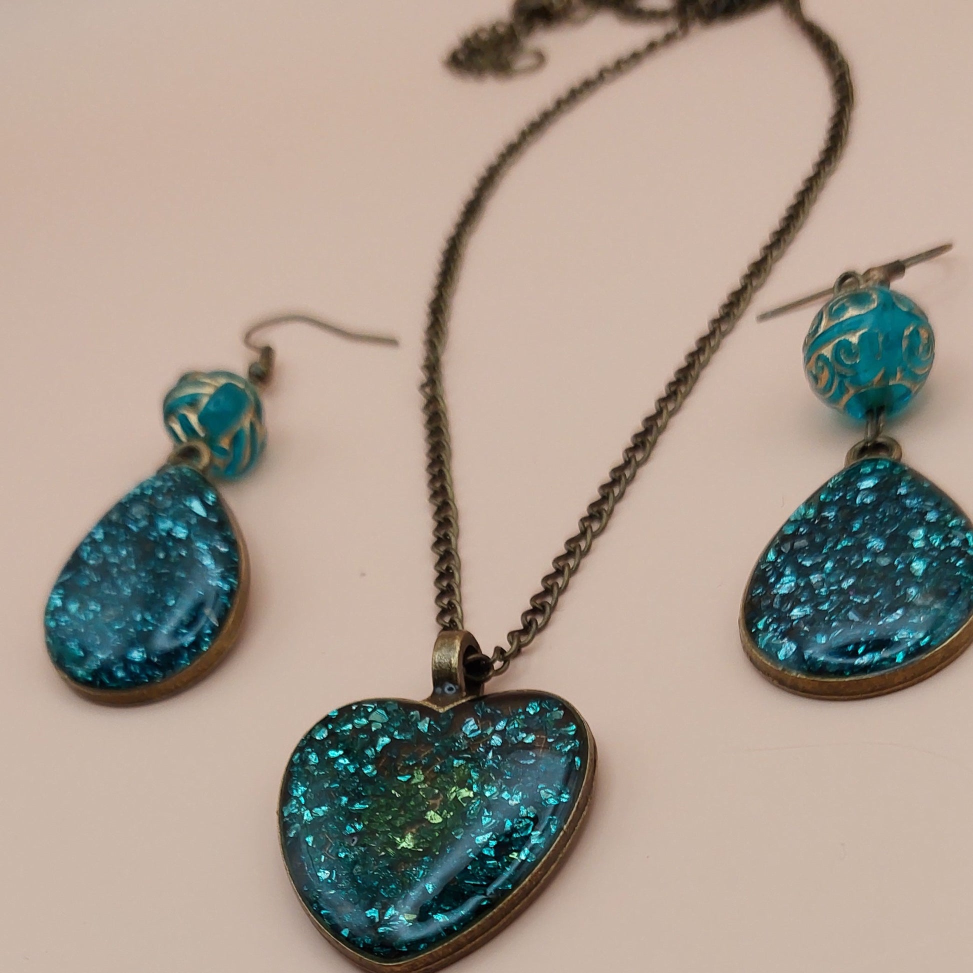 Teal druzy heart-shaped jewelry set on a beige background