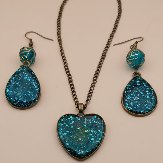 Jewelry set with blue glittery teardrop earrings and necklace on a beige background
