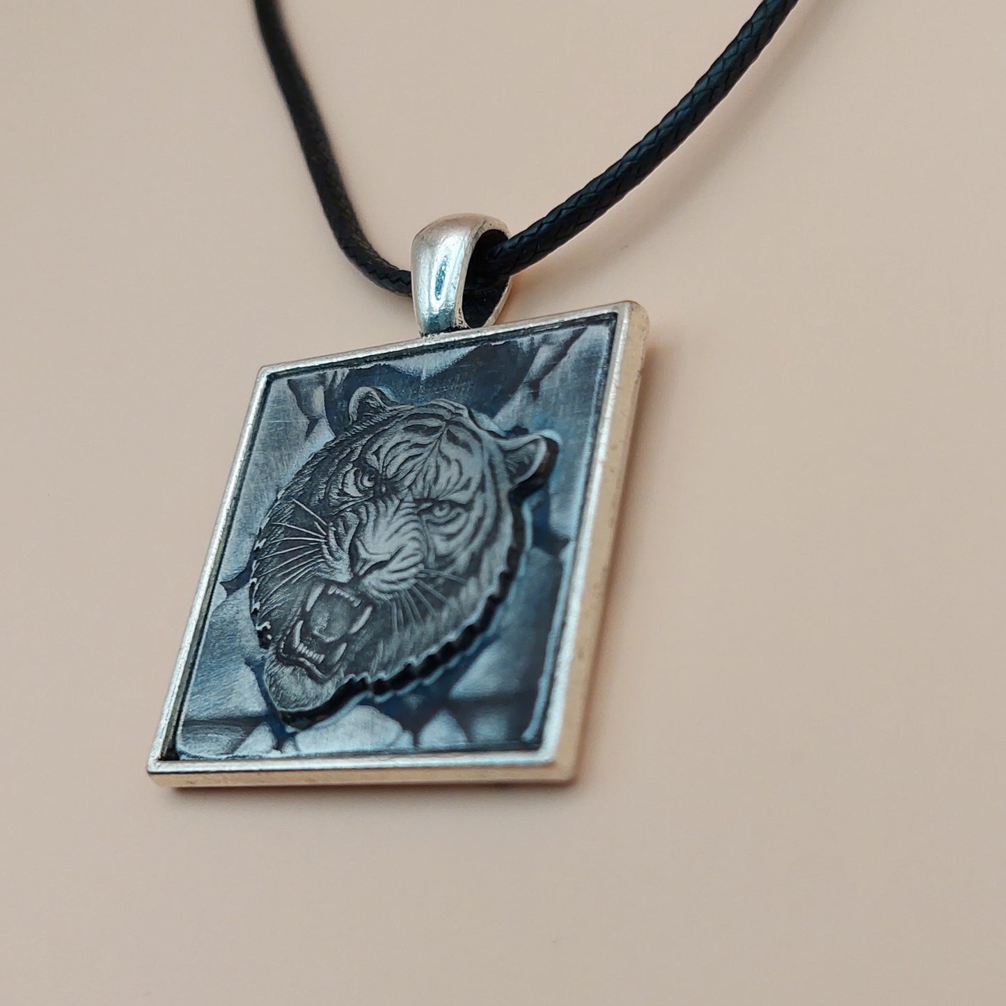 Necklace with a square pendant featuring an embossed design on a beige background