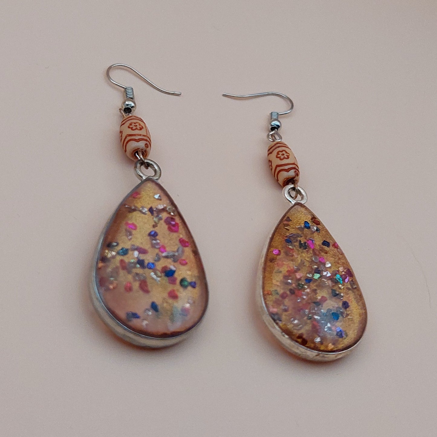 Teardrop-shaped earrings with floral pattern on a beige background