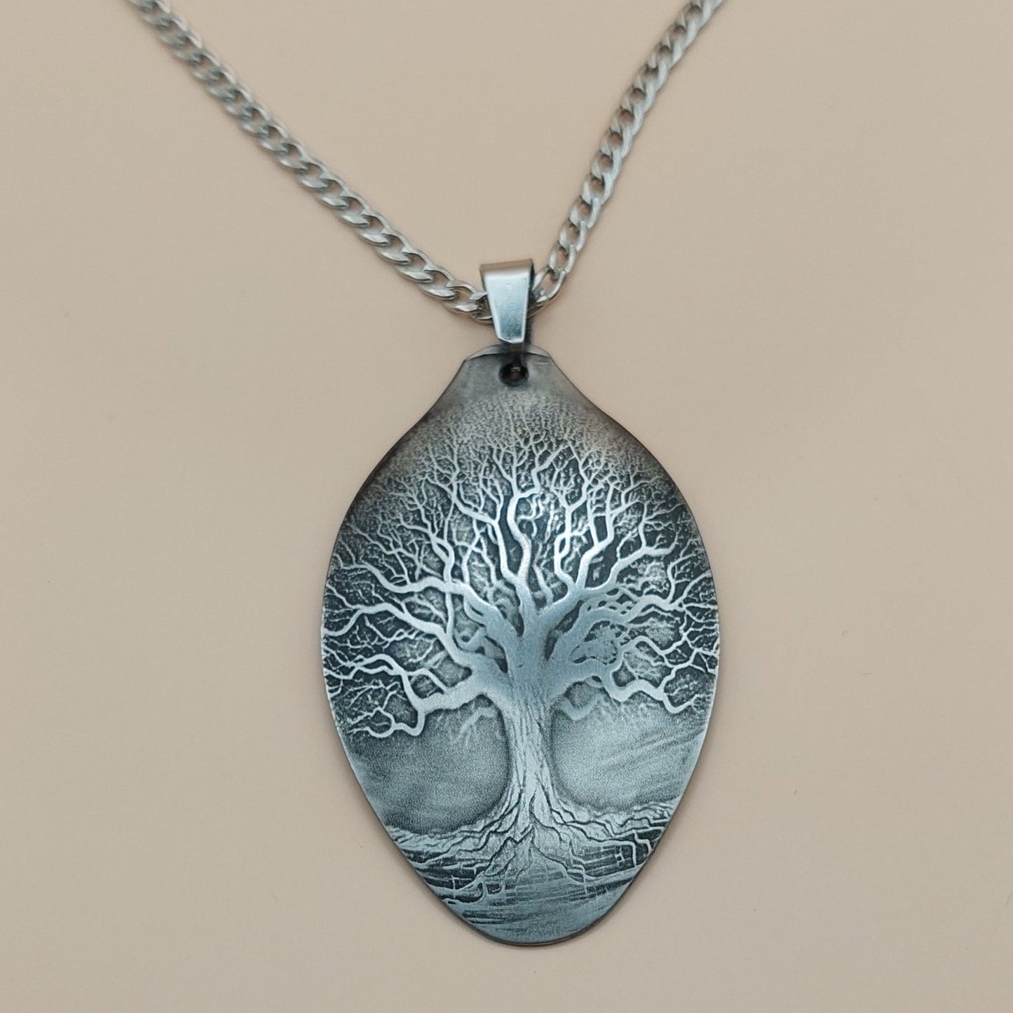 Silver necklace with a tree pendant on a beige background