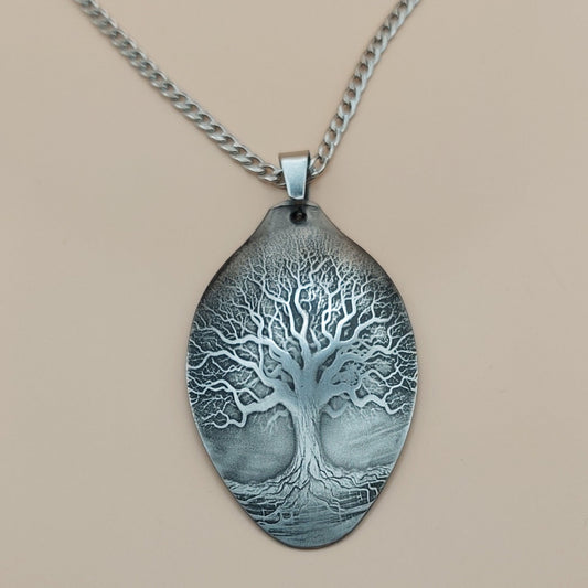 Silver necklace with a tree pendant on a beige background